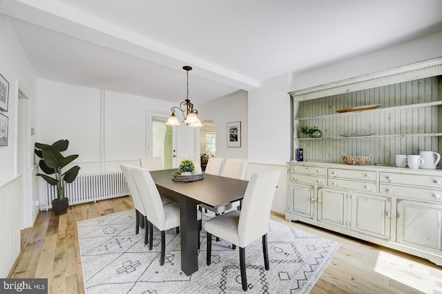 dining area with light wood-style flooring, radiator, and a notable chandelier