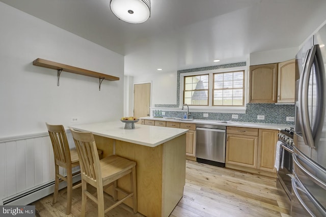 kitchen featuring a sink, light countertops, a breakfast bar area, and stainless steel appliances