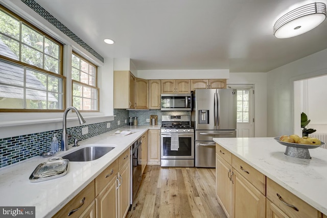 kitchen featuring a sink, appliances with stainless steel finishes, light stone countertops, and a healthy amount of sunlight