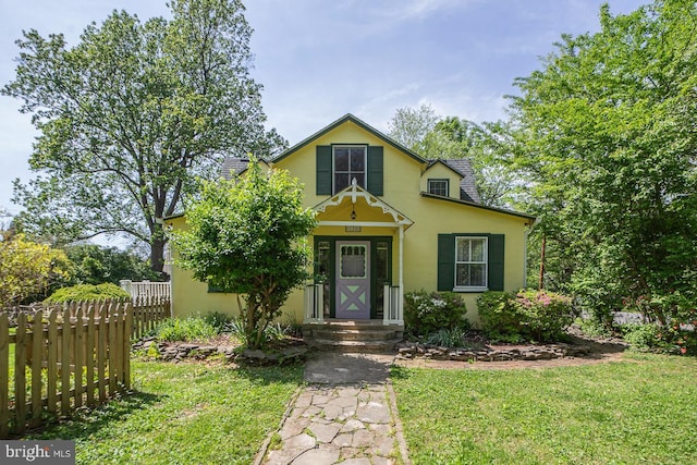 view of front of house featuring fence, stucco siding, and a front yard