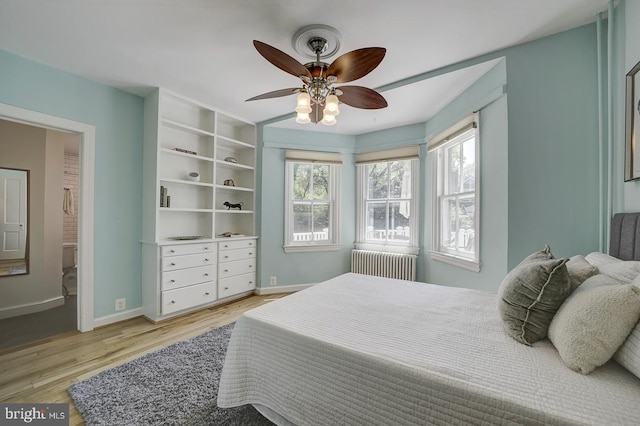 bedroom featuring radiator heating unit, baseboards, a ceiling fan, and light wood-type flooring