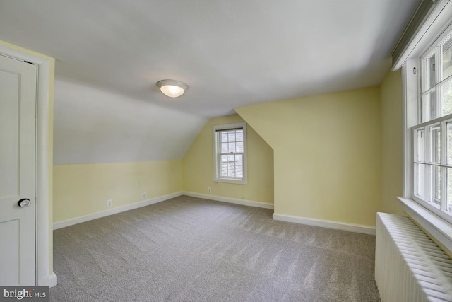 additional living space with baseboards, carpet flooring, radiator heating unit, and vaulted ceiling