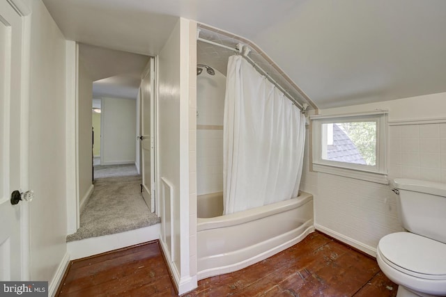 bathroom with vaulted ceiling, baseboards, toilet, shower / tub combo with curtain, and hardwood / wood-style floors