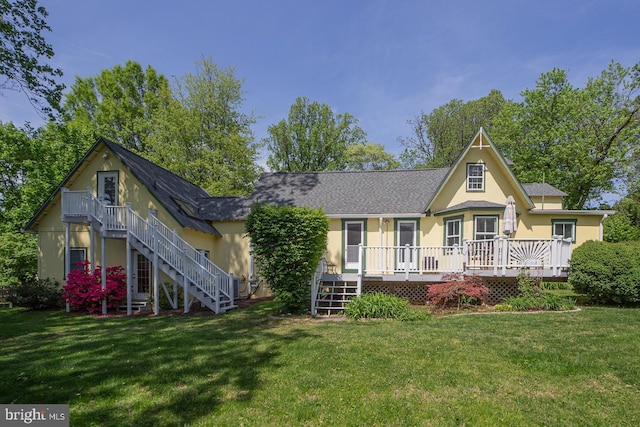 rear view of property featuring stairs, stucco siding, a yard, and a wooden deck