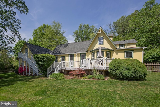 rear view of house with a lawn, a deck, stairway, fence, and stucco siding