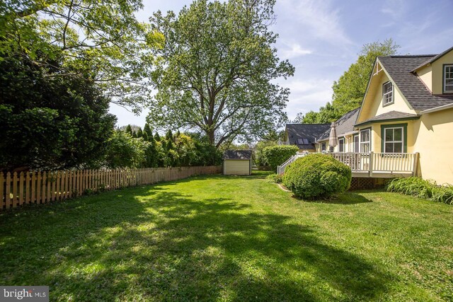 view of yard featuring a storage shed, fence, an outbuilding, and a wooden deck