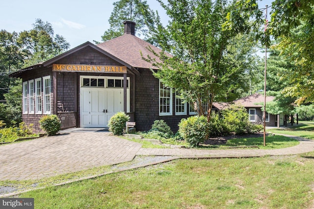 view of front of home with a chimney, a shingled roof, and a front yard