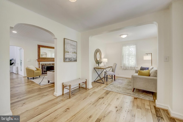 hall with arched walkways, baseboards, and wood finished floors