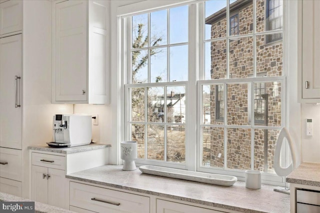 interior space with light stone counters and white cabinetry