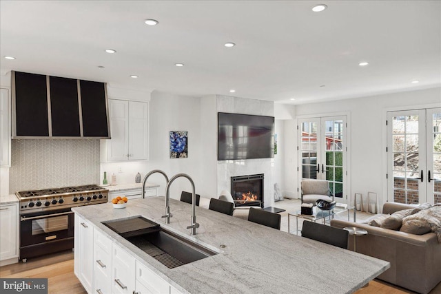 kitchen with a sink, high end stainless steel range oven, open floor plan, and french doors