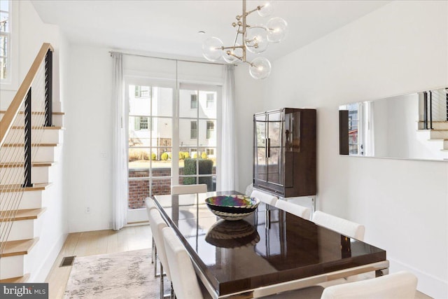 dining room with stairs, an inviting chandelier, visible vents, and light wood-type flooring