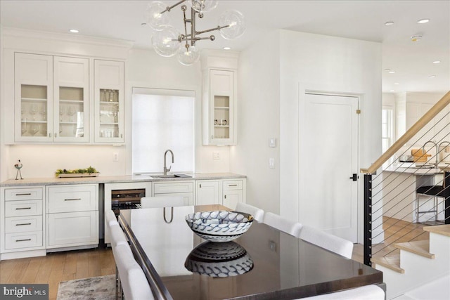 kitchen with white cabinetry, glass insert cabinets, wood finished floors, and a sink