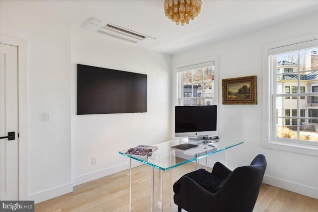 office featuring visible vents, a healthy amount of sunlight, baseboards, and wood finished floors