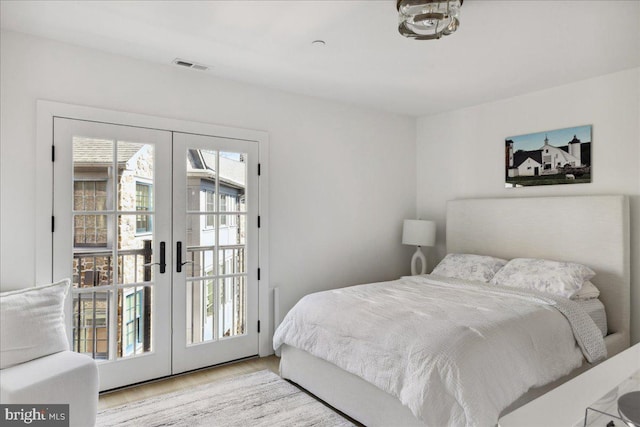 bedroom featuring access to exterior, wood finished floors, french doors, and visible vents