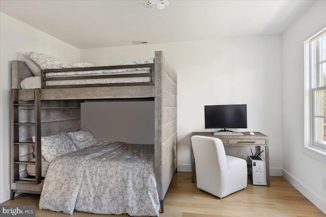 bedroom with wood finished floors, visible vents, and baseboards