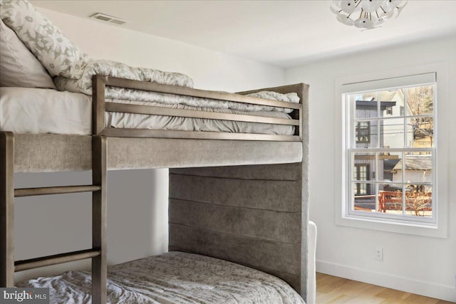 bedroom featuring wood finished floors, visible vents, and baseboards