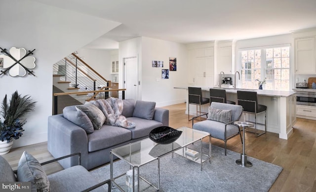 living room with stairway, baseboards, and light wood-type flooring