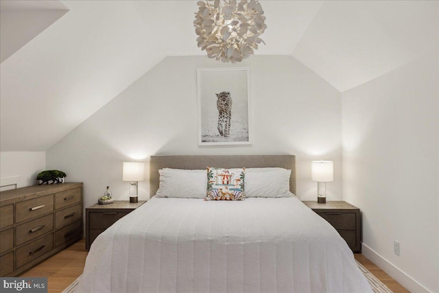 bedroom featuring vaulted ceiling, baseboards, and light wood-type flooring