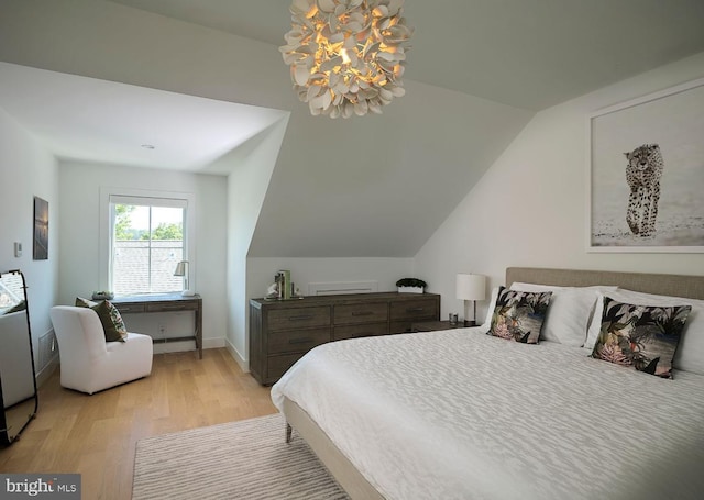 bedroom featuring light wood-type flooring, baseboards, and vaulted ceiling