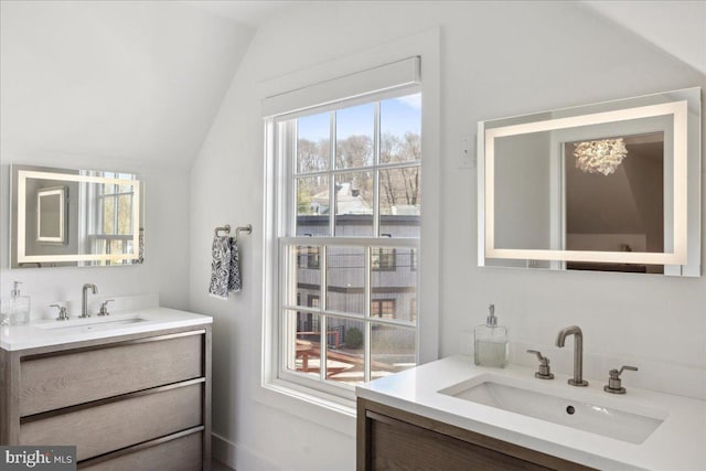 bathroom with lofted ceiling, two vanities, and a sink