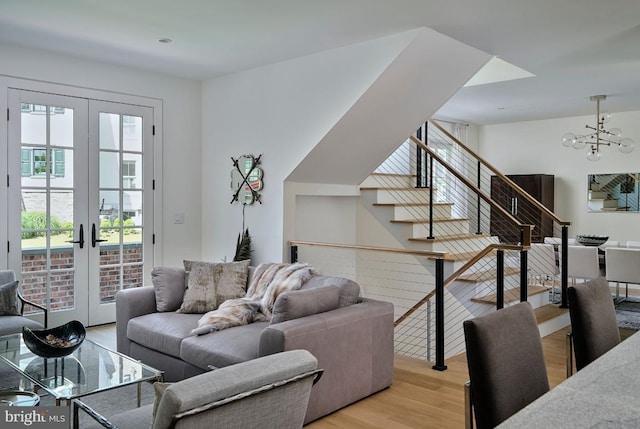 living room with french doors, a chandelier, stairs, and light wood finished floors