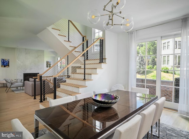 dining room with stairway, a notable chandelier, wood finished floors, and a high end fireplace