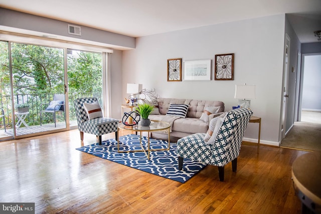 living room featuring wood finished floors, visible vents, and baseboards