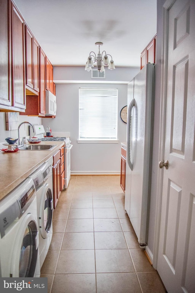 clothes washing area with washer and clothes dryer, light tile patterned floors, visible vents, a sink, and a chandelier