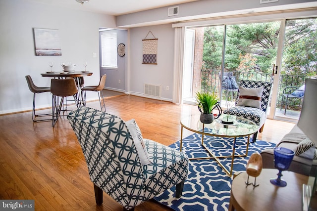 living area featuring visible vents, baseboards, and wood finished floors