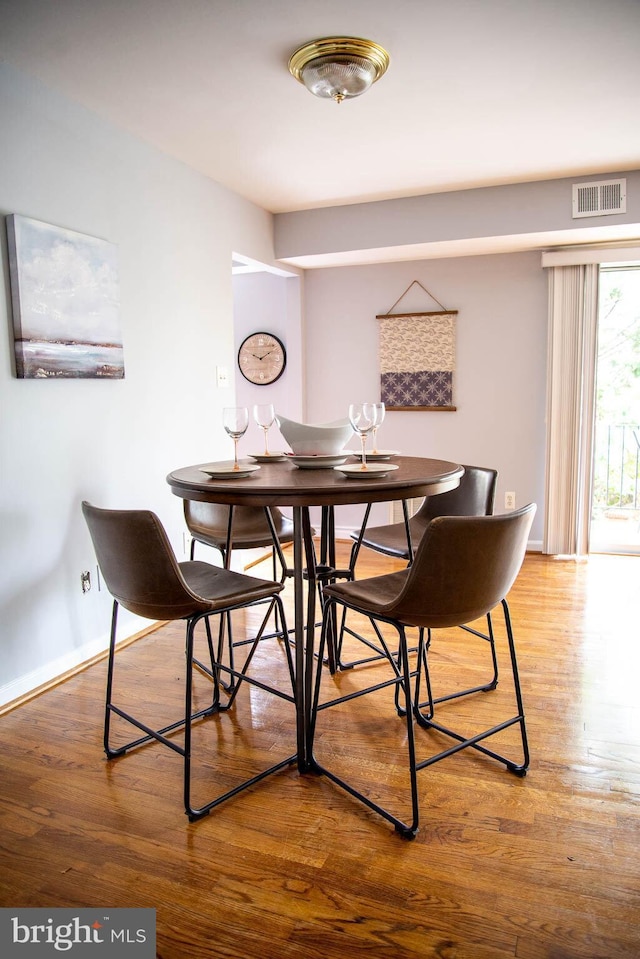 dining space featuring baseboards, visible vents, and wood finished floors