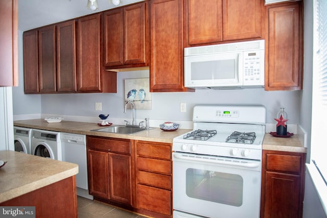 kitchen with white appliances, washing machine and clothes dryer, tile patterned floors, light countertops, and a sink