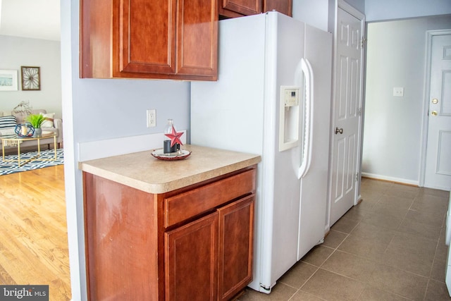 kitchen with brown cabinets, white fridge with ice dispenser, and light countertops