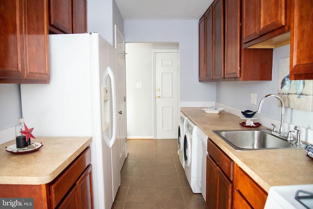 kitchen featuring independent washer and dryer, light countertops, a sink, and white refrigerator with ice dispenser