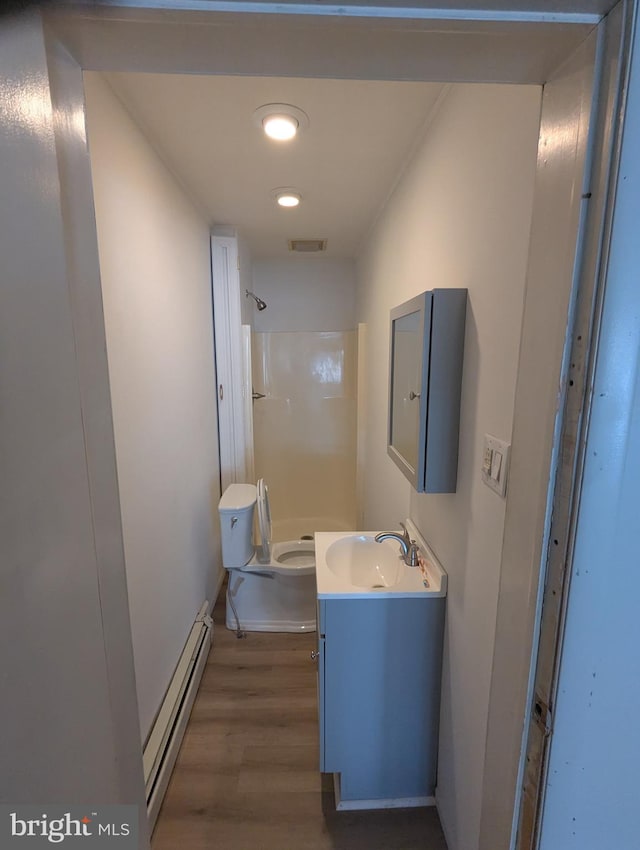 full bathroom featuring a baseboard heating unit, wood finished floors, visible vents, vanity, and a shower