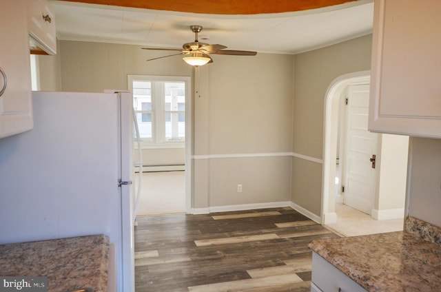 kitchen with a baseboard heating unit, freestanding refrigerator, white cabinetry, ceiling fan, and wood finished floors