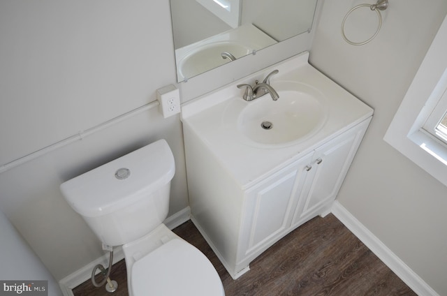 half bath featuring toilet, baseboards, wood finished floors, and vanity