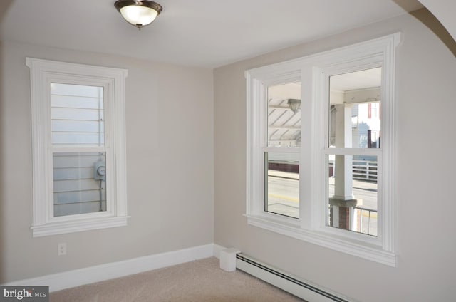 spare room featuring a baseboard radiator, carpet flooring, and baseboards