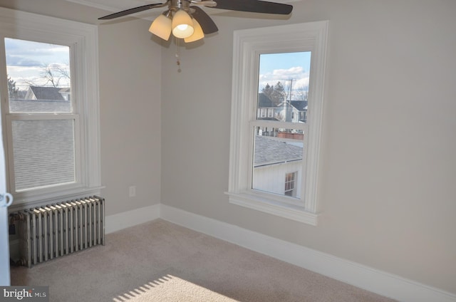 carpeted empty room featuring baseboards, a healthy amount of sunlight, and radiator heating unit