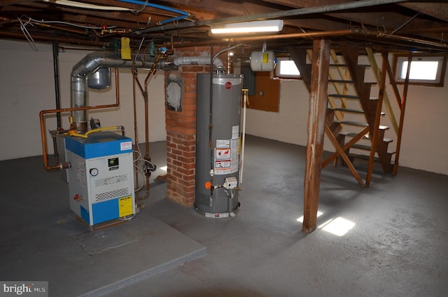 below grade area featuring a healthy amount of sunlight, water heater, and stairs