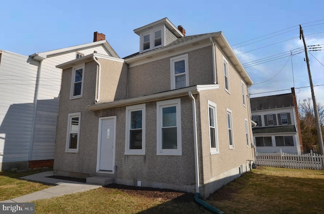 view of front facade featuring entry steps, a front yard, and stucco siding