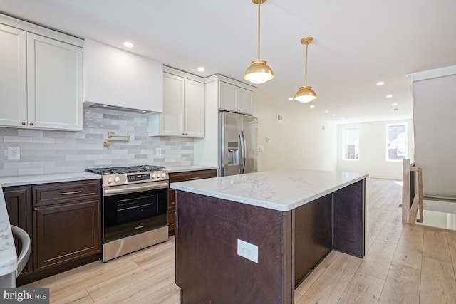 kitchen featuring stainless steel appliances, white cabinets, light wood-style floors, and backsplash