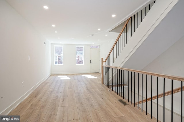 unfurnished living room with recessed lighting, visible vents, stairway, light wood-style floors, and baseboards