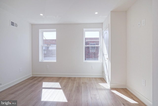 empty room featuring a healthy amount of sunlight, light wood-style floors, and visible vents