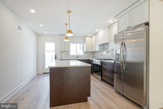 kitchen featuring light wood-style floors, tasteful backsplash, appliances with stainless steel finishes, and a sink