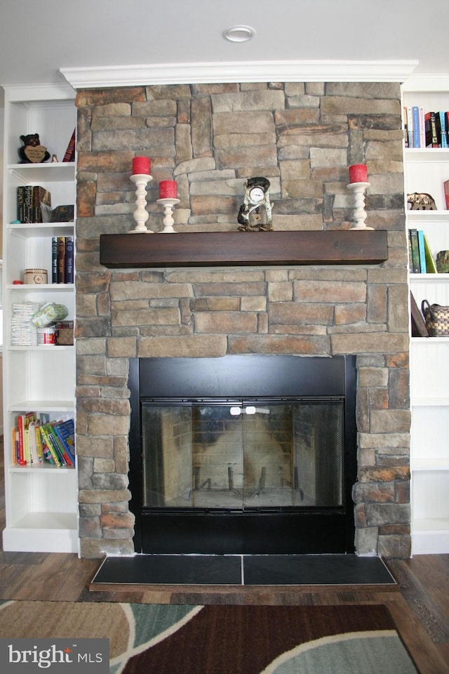 room details with a stone fireplace, wood finished floors, and built in features