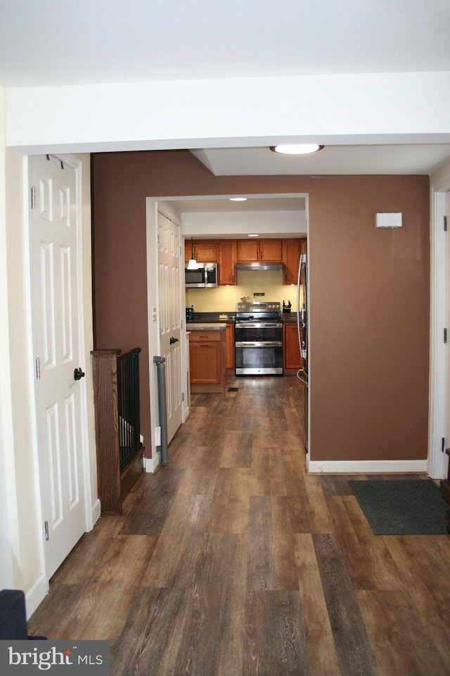 hall featuring dark wood-type flooring and baseboards