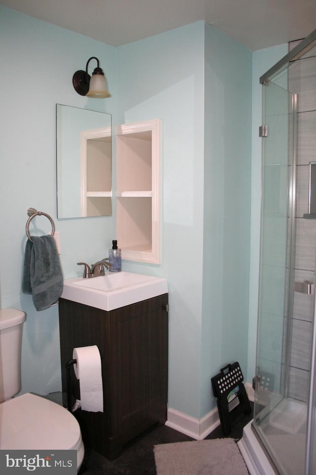 full bath featuring a stall shower, baseboards, vanity, and toilet