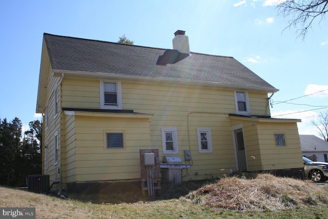 rear view of property featuring roof with shingles, a chimney, and central air condition unit