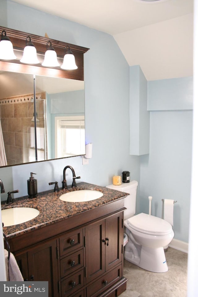 full bathroom featuring double vanity, a sink, toilet, and walk in shower