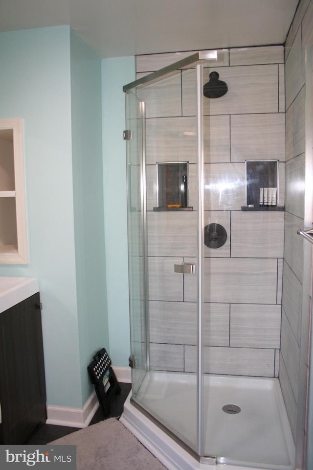 bathroom with a stall shower, baseboards, and vanity